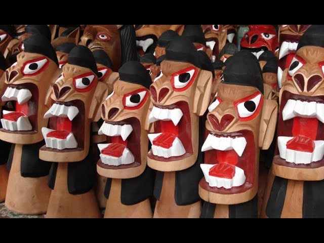 Dozens of brightly painted carrancas packed together — black manes and bodies, eyes outlined in red, and wide mouths painted red inside with oversized white teeth and fangs.